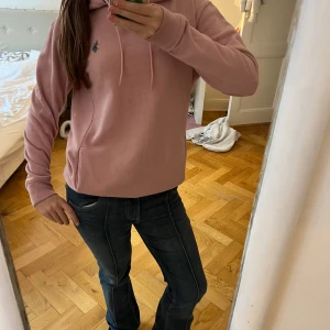 Rosa hoodie från U.S. Polo Assn. - Säljer en ljusrosa hoodie från U.S. Polo Assn. med broderad logga på bröstet. Tröjan har en klassisk passform och är tillverkad i mjuk bomullsmix. använd fåtal gånger säljer för 200kr