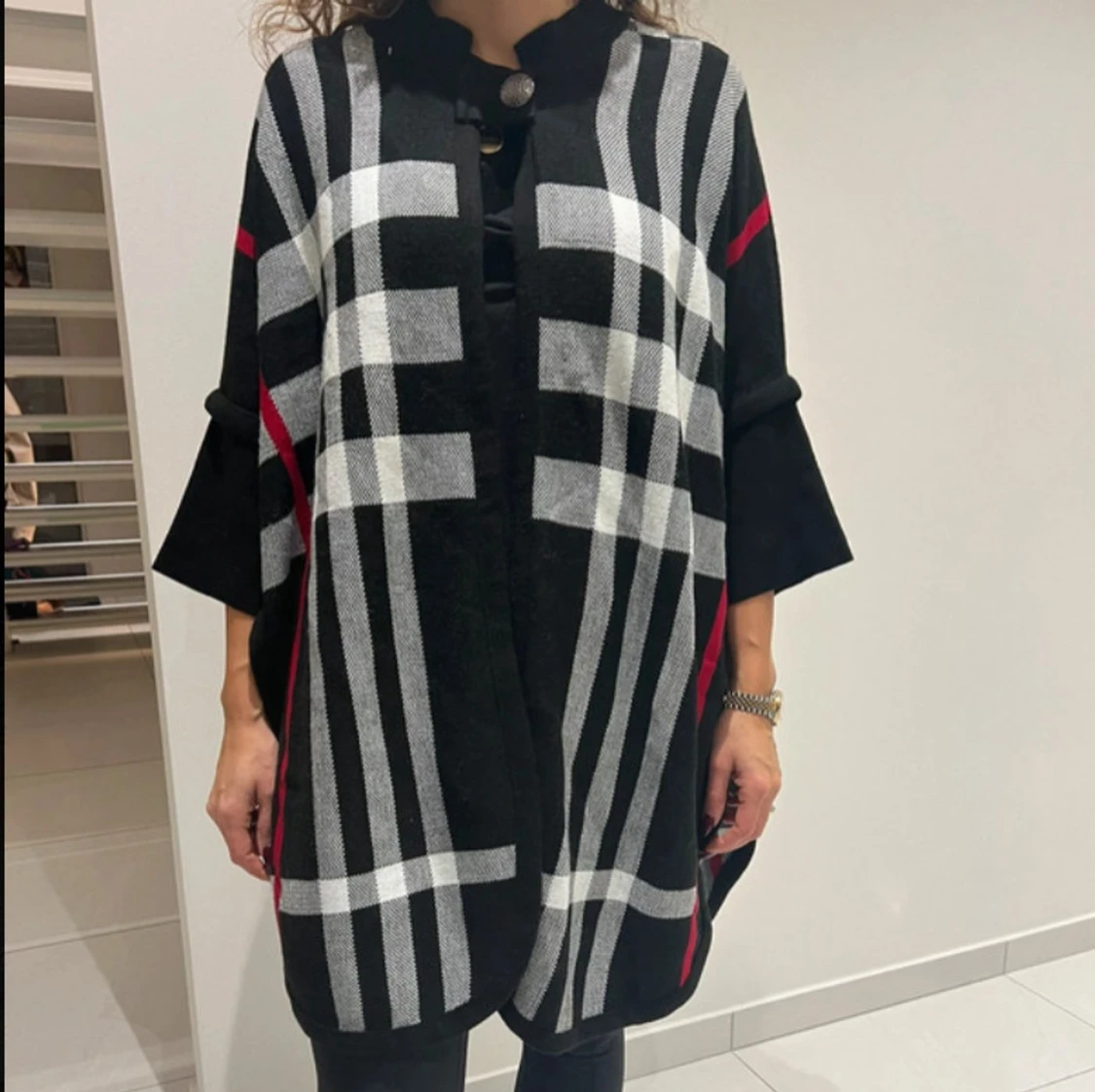 Svart och vit rutig poncho/kappa med röda detaljer