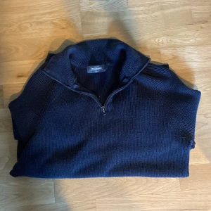 Mörkblå stickad tröja med dragkedja från Dressmann - Säljer en mörkblå stickad tröja från Dressmann i storlek S. Tröjan har halv dragkedja vid kragen och långa ärmar. Perfekt för lager-på-lager och enkel att matcha med jeans eller chinos.