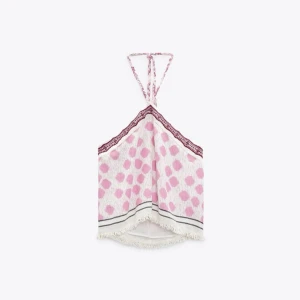 Mönstrad halterneck topp från Zara - Säljer en söt halterneck topp från Zara med rosa prickigt mönster och dekorativ spetskant upptill. Toppen har fransdetaljer nertill och knyts i nacken. Perfekt till sommaren 💞 tröjan är knappast använd, nypris är 329kr.