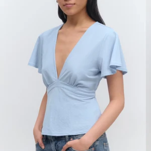 Ljusblå v-ringad topp med knytband - Snygg ljusblå v-ringad topp. Toppen har knytband i midjan som ger en fin passform. Aldrig använd💞