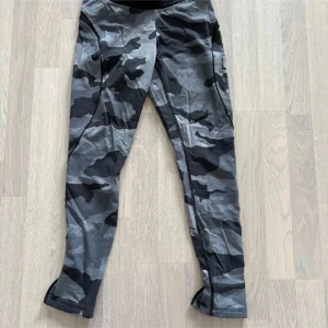 Camo leggings från Better Bodies - Säljer ett par grå och svarta camo-mönstrade leggings från Better Bodies. De har tight passform och är tillverkade i ett stretchigt material med hög andel polyamid och elastan. Perfekta för träning och har logga längs benet.