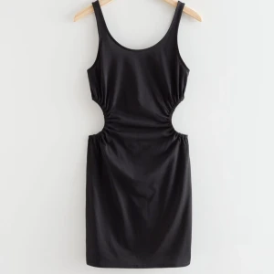 Svart tight kortklänning med cut-out detaljer - Säljer en svart tight kortklänning med rund halsringning och snygga cut-out detaljer i midjan. Klänningen är ärmlös och har en enkel, stilren design som passar perfekt till sommarens alla tillfällen. Nypris 690 kr. 