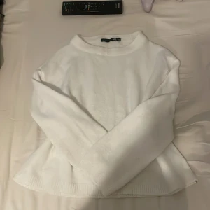 Vit stickad tröja från 157 - Säljer en enkel och stilren vit stickad tröja från 157 i storlek XS. Tröjan har lång ärm, rund halsringning och ribbade kanter vid ärmslut och nederkant. Perfekt basplagg till garderoben.