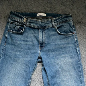 Blå bootcut jeans från Pull&Bear - Snygga blå jeans från Pull&Bear i klassisk bootcut-modell. Jeansen har fem fickor, bälteshällor och stängs med knapp och dragkedja. Tillverkade i jeansmaterial med lätt tvättad look och kontrastsömmar. Tycker dessa är skitsnygga men är tyvärr för stora för mig, därav är de sällan använda - i mycket bra skick. Storlek 44 men är rätt säker att de passar många i 42 och 40 också.