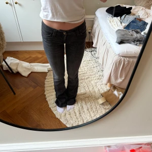 Svarta bootcut jeans  - Säljer ett par svarta bootcut jeans med klassisk femficksdesign och låg midja. Jeansen har en snygg passform som sitter tight upptill och släpper ut vid bensluten. Perfekta till vardags med en enkel t-shirt.