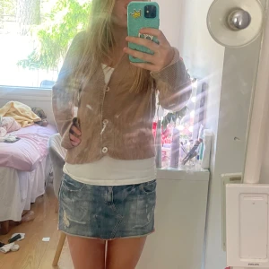 Beige stickad kofta från Karen Millen - Säljer en beige stickad kofta från Karen Millen med v-ringning och stora knappar framtill. Storlek är M/L men jag har S storlek. Koftan har långa ärmar och ribbade muddar vid ärmslut och nederkant. Perfekt att slänga över en t-shirt för en avslappnad look.