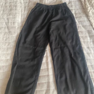 Svarta byxor från H&M - Svarta mjukisbyxor från H&M i storlek 152. Byxorna har resår i midjan och raka ben med en loose fit. Tillverkade med fickor på sidorna, perfekta för en chill och avslappnad stil.