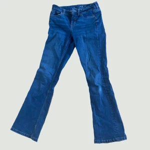 Mörkblå bootcut jeans - Snygga blå bomull jeans från Kappahl med mid waist midja. Skulle säga att de är en blandning av bootcut/straightleg! Uppskattar till strl 34