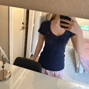 Marinblå topp från Ralph Lauren - Snygg marinblå topp från Ralph Lauren med v-ringning och korta ärmar. Klassisk röd broderad logga på bröstet. Modellen är figurnära och passar perfekt till jeans eller kjol. Mjuk och stretchig bomullskvalitet som känns skön mot huden. Är i nyskick och passar både XS och S. (Tröjan är inte smutsig det är spegeln💗) Skriv gärna om du har fler frågor💗💗 Pris kan diskuteras.