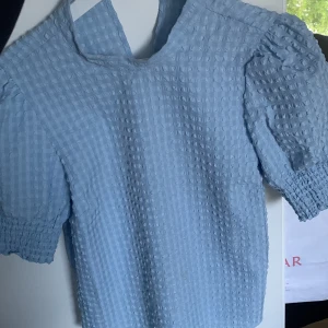 Ljusblå rutig blus från Vero Moda - Supersöt ljusblå blus från Vero Moda med rutigt strukturmönster 💫 Puffiga korta ärmar med smock vid ärmslut - Storlek: S ❣️