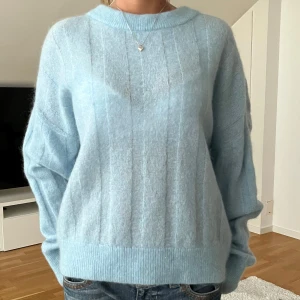 Ljusblå stickad tröja från H&M - Supermjuk ljusblå stickad tröja från H&M i mohairblandning. Tröjan har rund halsringning, diskreta lodräta ränder och långa ärmar. Perfekt för lager-på-lager och en chill look.