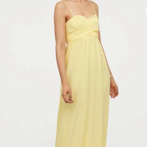 Ljusgul långklänning med smala axelband - Superfin ljusgul långklänning med smala axelband och omlott-detalj över bysten, man kan dessutom ta bort banden.
