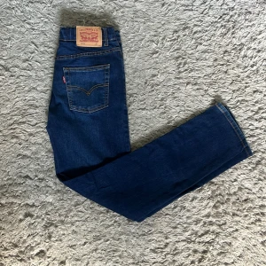 Levi's 512 blå jeans - Säljer ett par klassiska blå Levi's 512 jeans med raka ben och normal passform. Jeansen har fem fickor, synliga sömmar och en ikonisk läderpatch bak i midjan. Perfekta för dig som gillar tidlös denimstil. Använda väl och har inga större tecken på slitage. Skriv gärna om ni har frågor. 