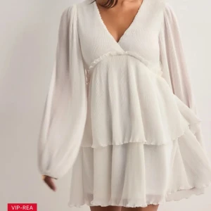 Vit klänning med volanger - Säljer denna superfina vita klänning med v-ringning och långa, luftiga ärmar. Perfekt till student🩷aldrig använt! Hör gärna av er vid intresse🩷