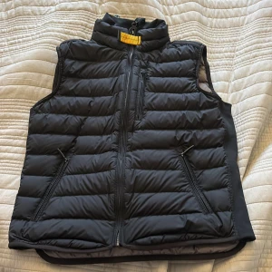Svart dunväst från Parajumpers, pris diskuteras!!! - Säljer en svart dunväst från Parajumpers med ståkrage och dragkedja framtill. Västen har två snedställda fickor med dragkedja och quiltad design. Insidan är ljusgrå och har märkets logga på nacken.