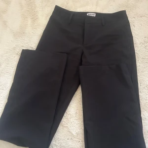 Svarta kostymbyxor från Madlady - Svarta kostymbyxor från Madlady i storlek EU34/Tall. Byxorna har raka ben, bälteshällor och klassisk design. Perfekta för en clean och stilren look. Materialet känns mjukt och följsamt, vilket gör dem bekväma att bära hela dagen.