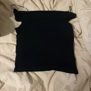 Svart axelbandslös tubtopp - En stilren svart tubtopp med axelbandslös bandeau-modell. Perfekt för att skapa en clean och enkel look. Toppens raka form gör den lätt att matcha med både jeans och kjol.