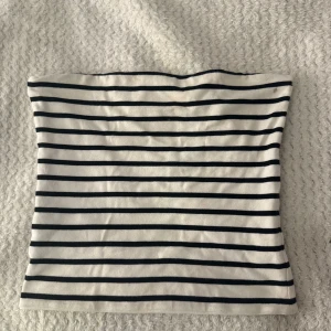 Randig tubtopp från BikBok - Säljer en vit och svart randig tubtopp från BikBok i storlek L. Toppen är bandeau-modell och ärmlös, perfekt för en chill och stilren look. Gjord i mjuk bomullsmix som sitter skönt mot huden. Enkel att matcha med jeans eller kjol.