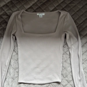 Beige långärmad topp från Amisu - Supersnygg beige topp från Amisu med lång ärm och fyrkantig urringning. Toppens material är stretchigt och sitter fint passar även S och xs 