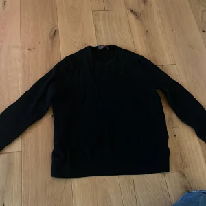 Svart stickad tröja med rund hals - En klassisk svart stickad tröja med rund hals och långa ärmar. Perfekt för lager-på-lager och funkar till det mesta. Enkel och stilren design som passar till jeans eller kjol.