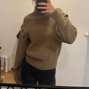  Stickad tröja med knappar - Brun stickad tröja med hög krage och knappar längs axlarna. Går även att ta av ärmarna om man hellre vill bära den som en väst. Sparsamt använd! 💕
