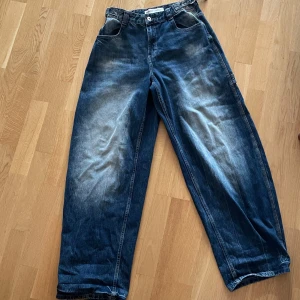 Baggy jeans - Säljer ett par baggy blå jeans från Bershka i storlek 40. De har bred passform, stora fickor, med ett justerbart bälte i midjan. Jeansen är tyvärr för långa för mig som är 164 cm men skulle passa perfekt för dig som är runt 175 cm lång!!