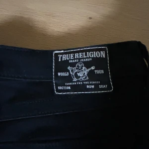 Svarta bootcut jeans från True Religion - Svarta jeans från True Religion med snygga detaljer på både bak och framfickorna. De är i storlek 30 så skulle säga att de passar M❤️
