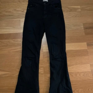 Svarta bootcut jeans - Svarta jeans med bootcut-modell och klassisk femficksdesign. Byxorna har hög midja och är tillverkade i ett mjukt bomullstyg med lite stretch. Perfekta för dig som gillar en retro vibe och vill ha ett par jeans som sticker ut lite extra. 