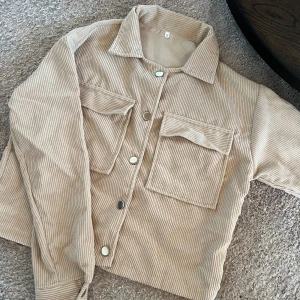Oanvänd beige jacka - Beige sommarjacka i manchestertyg med silvriga knappar som är helt oanvänd.