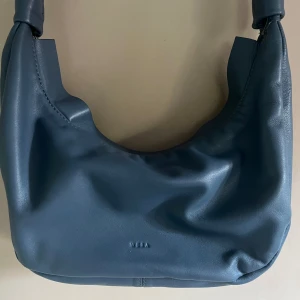 Blå crossbodyväska - Snygg blå vrossbodyväska från VERA i mjukt skinn. Perfekt storlek och får plats med mycket mer än vad man kan tro! Knappt använd, nypris 800.