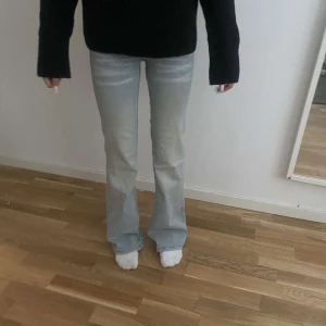 Ljusblå bootcut jeans från Cheap Monday - Säljer ett par ljusblå jeans från Cheap Monday med bootcut passform och låg midja. Jeansen har snygga slitningar och en vit logopatch bak. Perfekta för dig som gillar en avslappnad och trendig look. Dessa är i storleken 23/30