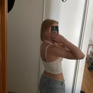 Vit ribbad halterneck linnetopp - Säljer en vit ribbad linnetopp med halterneck och djup urringning. Toppen är croppad och sitter tajt!🥰