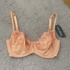 Aprikos spetsbh från LingaDore - Helt ny. Nypris 470kr    Superfin aprikosfärgad bh från LingaDore med vackra spetsdetaljer och broderade blommor upptill. Justerbara axelband och liten blomapplikation framtill. Sidenliknande material som känns lyxigt och mjukt mot huden.
