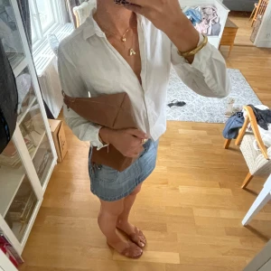 Blå jeanskjol - Säljer en blå jeanskjol i kort modell med stora, markerade fickor fram och bak. Kjolen har en klassisk jeanslook med synliga sömmar och knappstängning i midjan. Perfekt för dig som gillar en avslappnad och trendig stil. 