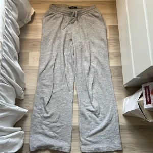 Grå mjukisbyxor från BikBok, storlek S - Superbekväma grå mjukisbyxor från BikBok i storlek S. Byxorna har resår och snörning i midjan samt raka, lite vidare ben. Perfekta för chill dagar eller när du vill ha en avslappnad stil. Tillverkade i mjukt bomullsmaterial.