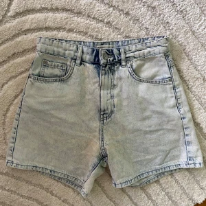 Ljusblå högmidjade jeansshorts - Helt ny, endast använda 2 ggr. Snygga ljusblå jeansshorts från Perfect Jeans i klassisk femficksmodell. Hög midja och raka ben ger en chill vibe. Shortsen har en tvättad look med tydliga sömmar och bälteshällor. Perfekta för varma dagar och enkel att matcha med allt. Se sista bild på andra jeansshorts jag säljer billigt. 
