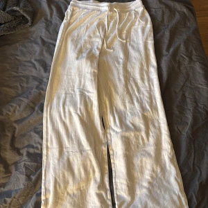 Vita linnebyxor från NA-KD XS - Säljer ett par vita linnebyxor från NA-KD i storlek XS. Byxorna har diskret randigt mönster, resår i midjan med snörning och är tillverkade i ett luftigt material som passar perfekt för varmare dagar.