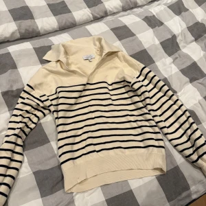 Randig tröja från & Other Stories - Snygg krämvit tröja från & Other Stories med marinblå horisontella ränder. Klassisk krage och långärmad modell i mjuk bomull. Perfekt för en chill och stilren look.