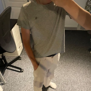 Grå Calvin Klein t-shirt, regular fit - Snygg grå t-shirt från Calvin Klein Jeans med liten svart CK-logga på bröstet. Modellen är regular fit och har klassisk rund hals och korta ärmar. Perfekt basic-plagg i mjuk bomull som funkar till allt. Står storlek 12 men jag är 163 och har xs så tror den är typ xxs 