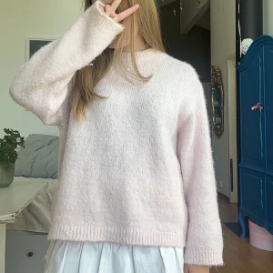 Ljusrosa stickad tröja från Gina Tricot - Supermjuk och fluffig ljusrosa stickad tröja från Gina Tricot. Tröjan har en rund halsringning och långa ärmar. Perfekt att mysa i under kyliga dagar och enkel att styla med både jeans och kjol.