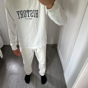 Vit sweatshirt från Gant med tryck - Vit sweatshirt från Gant med mörkblå HISTORY-tryck på bröstet. Klassisk rund halsringning med ribbade muddar vid ärmslut och nederkant. Skön passform och mjukt bomullsmaterial, perfekt för en clean och stilren look.