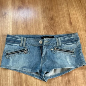 Lågmidjade jeansshorts - ❣️Intressekoll❣️Snygga blå jeansshorts med låg midja och coola dragkedjor framtill. Shortsen har slitna detaljer, bälteshällor och bakfickor med dekorativa sömmar. Perfekta för sommardagar när du vill ha en avslappnad och trendig look.