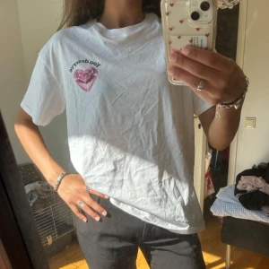 Vit t-shirt med rosa hjärta och text - Vit t-shirt med tryck av ett rosa discokulshjärta Klassisk passform och korta ärmar, perfekt för en chill och personlig stil. Storlek XS men den är större i storleken! Aldrig använd