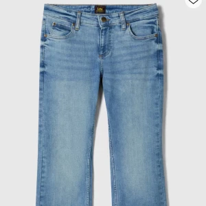 Ljusblå Lee jeans bootcut - Snygga ljusblå lågmidjade jeans från Lee med klassisk femficksdesign och bootcut-ben. Jeansen har normal passform, mellanblå tvätt och Lee-logga på bakfickan. Tillverkade i mjukt bomullsjeansmaterial med dragkedjegylf och bälteshällor. Jeansen är i modellen Jessica och de har använts sparsamt, och har därför inga defekter. Jeansen är även uppsydda av en sömmerska så att de passar mig som har en innerbenslängd på 74 cm ( se sömmen på sista bilden). Nypris- 1099 kr