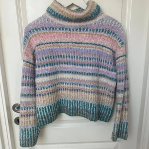 Randig pastellfärgad polotröja - Stickad polotröja i pastelliga färger som rosa, lila, blått och grönt. Tröjan har breda ränder, hög krage,  lång ärm och en bekväm passform:)