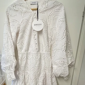 Vit broderad klänning från Joelle - Söt klänning från Joelle med broderade detaljer och v-ringning. Storlek 34, men passar även större då midjan är elastisk. Slutsåld online. Aldrig använd. Tillverkad av 100% bomull. Skriv till mig för fler bilder. 