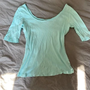 Ljusblå topp med bred urringning från Lindex - Säljer en ljusblå topp från Lindex med bred urringning och trekvartsärm. Toppens material är tunn och mjuk, perfekt för varmare dagar. Enkel och stilren design som passar till många olika outfits.