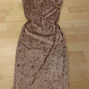 Champagnefärgad sammetsklänning från Joe & Elle - Säljer en snygg axelbandslös långklänning i champagnefärgad sammet från Joe & Elle. Klänningen har en figurnära passform och är perfekt för dig som vill sticka ut med en elegant look. Klänningen sitter rätt så tight 🌸