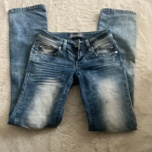 Ljusblå lågmidjade jeans  - Snygga blå jeansbyxor från Dromedar med slitningar och ljusa partier framtill. Byxorna har raka ben, nitar vid fickorna och dekorativa detaljer på bakfickan. I princip aldrig använda då de är för små för mig.